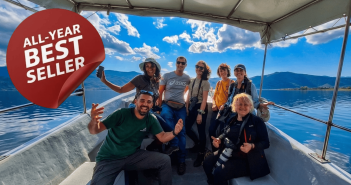 Tourists smiling and enjoying a scenic boat trip on Lake Kerkini to see pelicans.